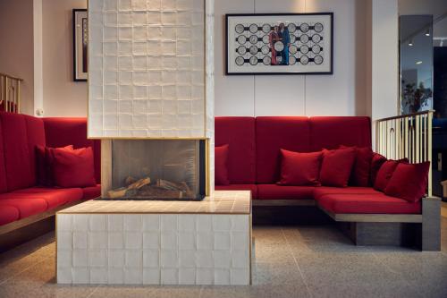 a living room with red couches and a fireplace at Kimpton De Witt Amsterdam, an IHG Hotel in Amsterdam