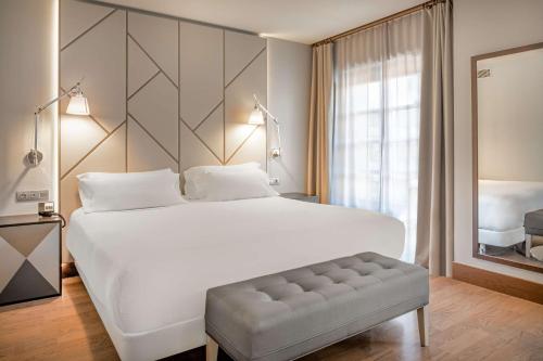 a bedroom with a large white bed and a large window at NH Collection León Plaza Mayor in León