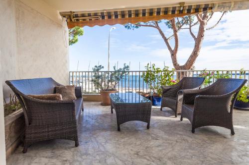 カンヌにあるIMMOGROOM- Huge Terrace - Panoramic Sea View - 1min from Beachの籐の椅子とテーブルと木のあるパティオ