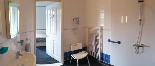 a bathroom with a shower and a toilet and a chair at Ty Castell Guest House in Caerphilly