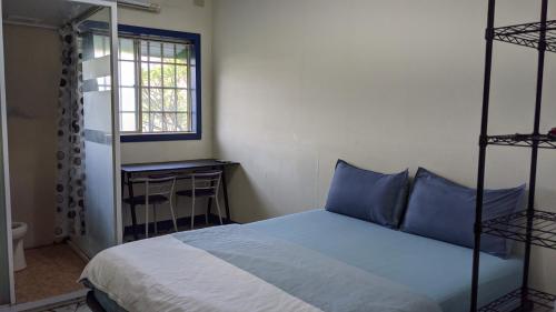 a bedroom with a bed with blue pillows and a window at 鐵騎休息棧 in Fangliao