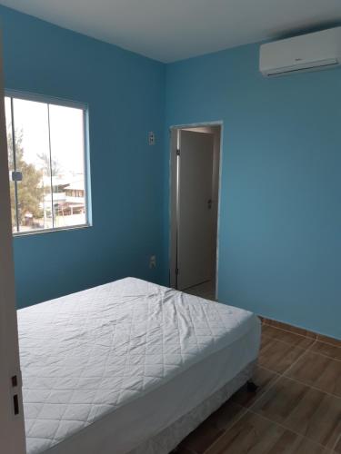 Dormitorio azul con cama y ventana en Pé na Areia (Monte Alto / Arraial do Cabo), en Arraial do Cabo