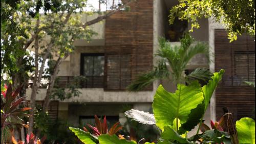 a building with a bunch of plants in front of it at Panacea Condo Tulum in Tulum