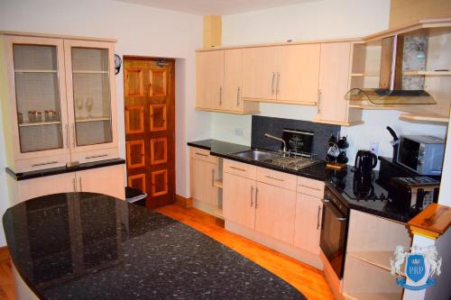 una cucina con armadietti bianchi e ripiani neri di Two Bedroom Town Centre Apartment a Elgin