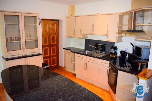 a kitchen with white cabinets and black counter tops at Luxury 2 Bed Serviced Apartment in Elgin