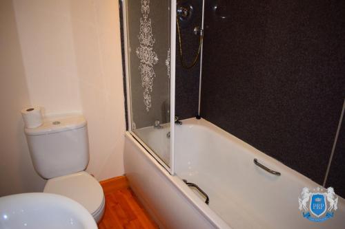 a bathroom with a toilet and a shower and a bath tub at Luxury 2 Bed Serviced Apartment in Elgin