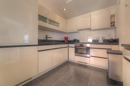une cuisine blanche avec des armoires et des appareils blancs dans l'établissement IMMOGROOM - Beautiful duplex - Sea view - Quiet - AC - Wifi - Garage, à Cannes