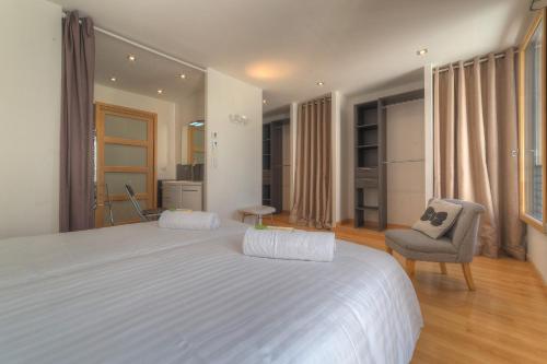 une chambre avec un grand lit blanc et une chaise dans l'établissement IMMOGROOM - Beautiful duplex - Sea view - Quiet - AC - Wifi - Garage, à Cannes