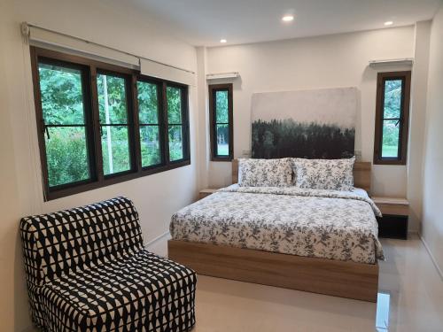 a bedroom with a bed and a chair and windows at Casa Khaoyai Bed&Breakfast in Mu Si