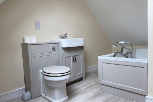 a white bathroom with a sink and a toilet and a tub at The Hideaway - Farm Stay with hottub, pool table and outdoor cinema in Newmilns