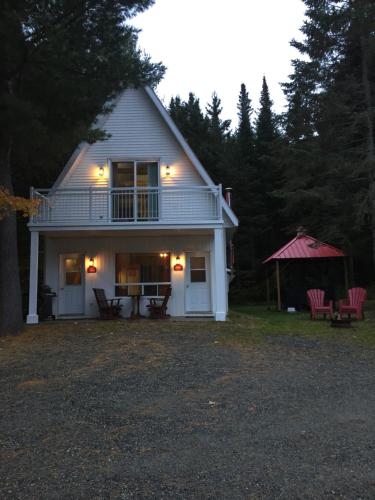 a white house with a porch and a gazebo at Aux Pignons Rouges Camping & Chalets in Saint Romain