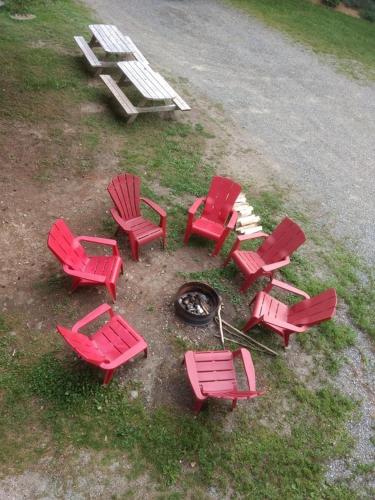 a group of red lawn chairs and a fire pit at Aux Pignons Rouges Camping & Chalets in Saint Romain