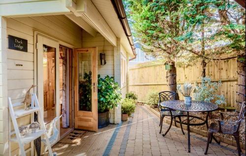 a patio with a table and chairs next to a house at Duck Lodge B&B with Hot Tub in Pyecombe