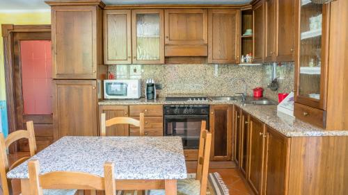 una cocina con armarios de madera y una mesa con sillas. en Casa Asfodeli - Villetta in campagna con piscina, en Cuglieri