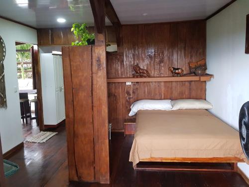 1 dormitorio con 1 cama con pared de madera en Cabana Luna en Jicaral