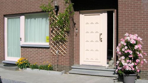 a brick house with a white door and flowers at Liry's Home in Tongeren