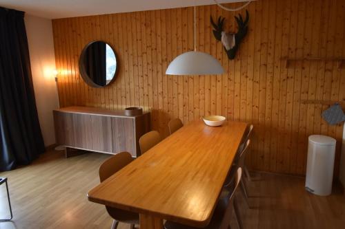 een eetkamer met een houten tafel en een spiegel bij VAUJANYLOCATIONS - Cochette 1 Apt 5 in Vaujany