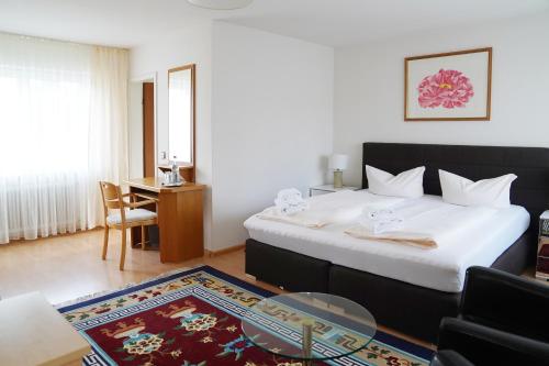 a bedroom with a large bed with a table and a chair at Hotel Hofmann Zur Mühle in Bad Krozingen