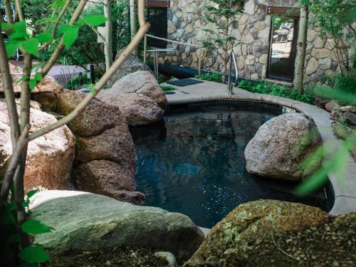 a pool of water with rocks in a garden at Lift One - Updated Cozy Top Floor Two-bedroom With Mountain View in Aspen