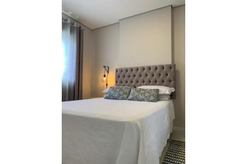 a bedroom with a large white bed with blue pillows at Suíte Master Collection in Passo Fundo