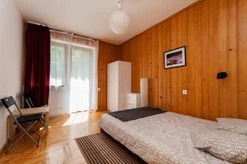a bedroom with wooden walls and a bed and a window at Krynica Zamkowa 48 in Krynica Zdrój