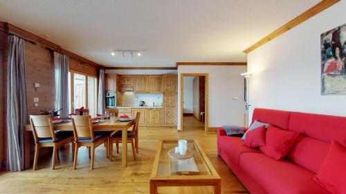 a living room with a red couch and a table at Hauts de Veysonnaz SAUNA & VIEW apartments in Veysonnaz