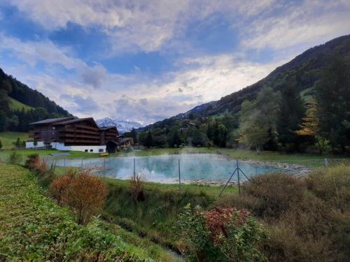 a lake in a field next to a building at Appartement et studio, Val d'illiez in Val dʼIlliez