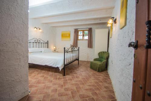 a bedroom with a bed and a green chair at La Finca Blanca in Alora
