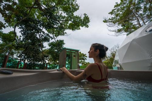 
a woman in a bathing suit sitting in a pool at Chira Glamping Monteverde in Monteverde Costa Rica
