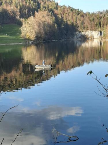 a man is in a boat on a lake at un ptit chalet in Les Brenets