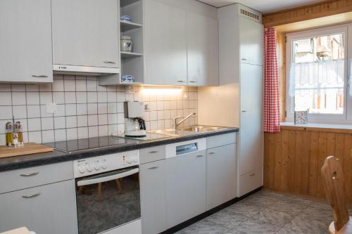 una cocina con armarios blancos y fregadero en Casa Curgnun 21 Collenberg - Ferienwohnung 61m2 für max. 4 Pers., en Morissen