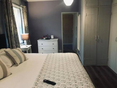 a bedroom with a white bed with a remote control on it at White Horse Farm Inn in Pickering