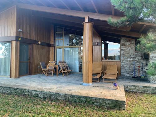 a house with a patio with chairs and a pillar at Pirin Golf Villa Emila in Bansko