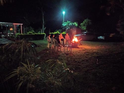 a group of people sitting around a fire at night at Hostal Payaca in Bituima