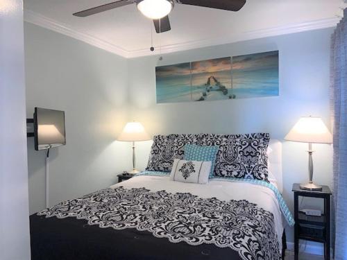 a bedroom with a bed and two lamps and a painting at Dockside Daze! in Galveston