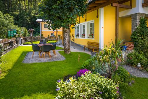 a garden with a table and chairs and flowers at Pension Appartements Gabriele in Bad Gastein