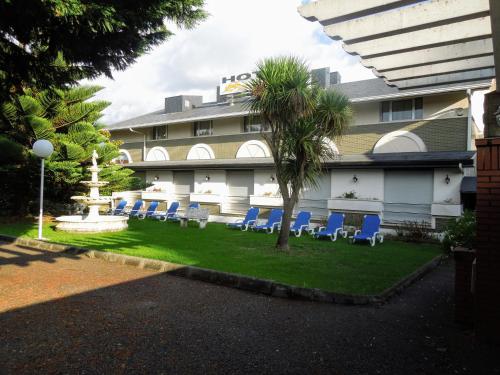 hotel z niebieskimi krzesłami, palmą i budynkiem w obiekcie Hotel Ría de Suances w mieście Suances