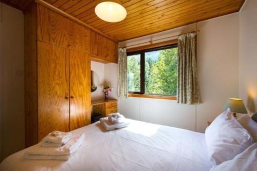 a bedroom with a large white bed with a window at 2 bedroom lodge sleeps 4 loch and mountain view in Crianlarich