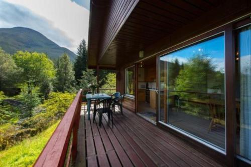 a wooden deck with a table and chairs on it at 2 bedroom lodge with stunning loch mountain views in Crianlarich