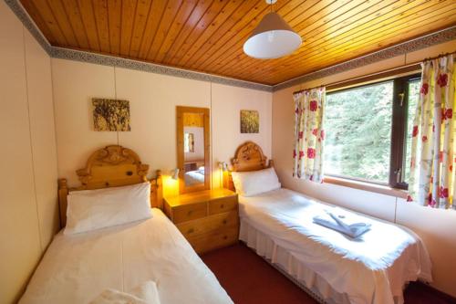 een slaapkamer met 2 bedden en een raam bij Heron chalet in Crianlarich