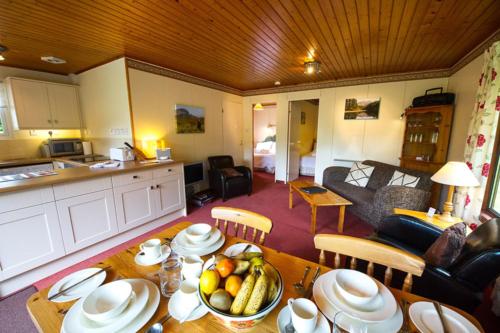 a kitchen and a living room with a table with fruit on it at Heron chalet in Crianlarich