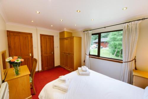 a bedroom with a white bed and a window at The Buzzard in Crianlarich