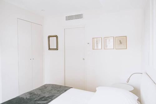 - une chambre blanche avec un lit et deux photos sur le mur dans l'établissement Les Suites de Catherine, la 35, à Nancy