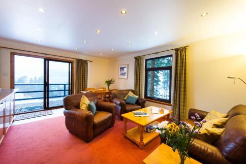 a living room with couches and a table at Osprey Lodge with river and mountain view in Crianlarich