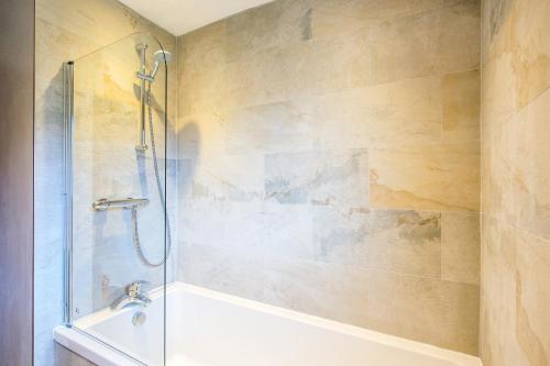 Un baño con ducha, bañera y lavabo. en Gamekeeper Lodge loch and mountain view free wifi, en Crianlarich