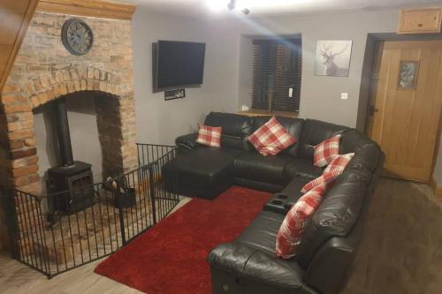 a living room with a black leather couch and a fireplace at Cosy Minffordd Let - Llanuwchllyn near, Bala LL23 in Bala