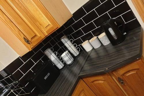 una barra de cocina con tres tazas de café. en Cosy Minffordd Let - Llanuwchllyn near, Bala LL23, en Bala