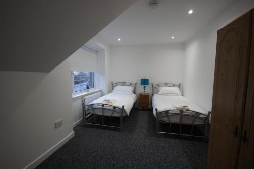 a room with two beds and a window at Loch Lomond Riverside Apartment in Drymen