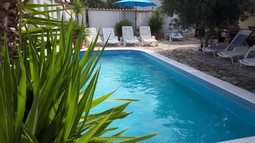 uma piscina com cadeiras e um guarda-sol num quintal em Fresh Apartments Dar Orlic em Trogir