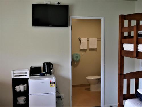 a room with a toilet and a television on a wall at Kaiteri Lodge in Kaiteriteri